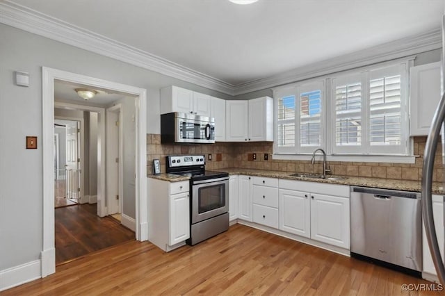 kitchen with white cabinets, light wood finished floors, appliances with stainless steel finishes, and a sink