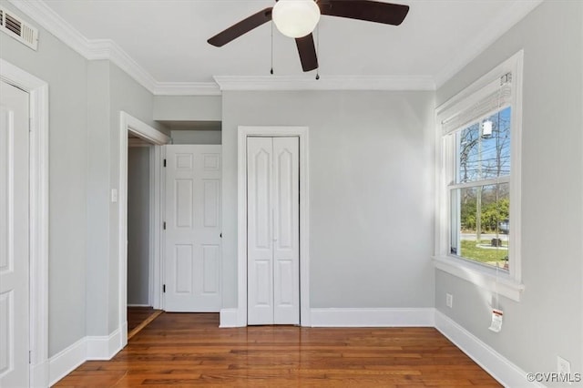 unfurnished bedroom with visible vents, crown molding, and wood finished floors