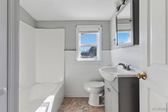 bathroom featuring vanity, toilet, marble finish floor, and wainscoting