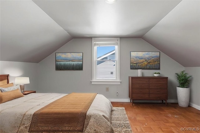 bedroom with lofted ceiling and baseboards