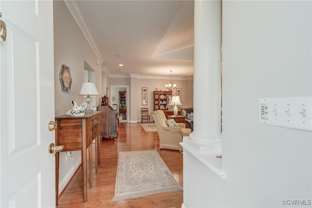 interior space featuring ornate columns, an inviting chandelier, light wood-style flooring, and ornamental molding