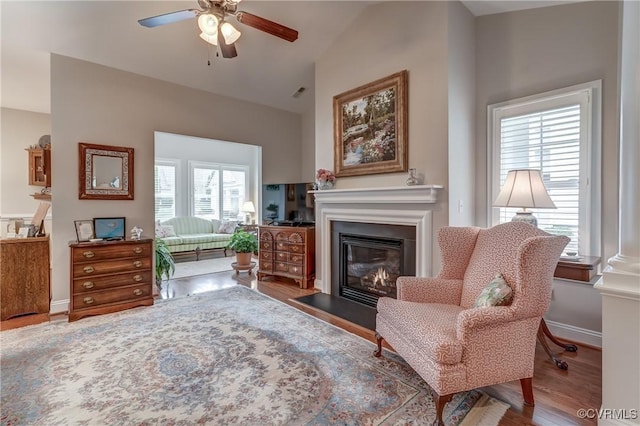 sitting room featuring visible vents, ceiling fan, baseboards, a fireplace with flush hearth, and wood finished floors