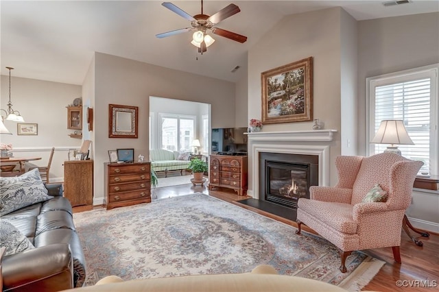 living area featuring visible vents, a fireplace with flush hearth, high vaulted ceiling, wood finished floors, and ceiling fan