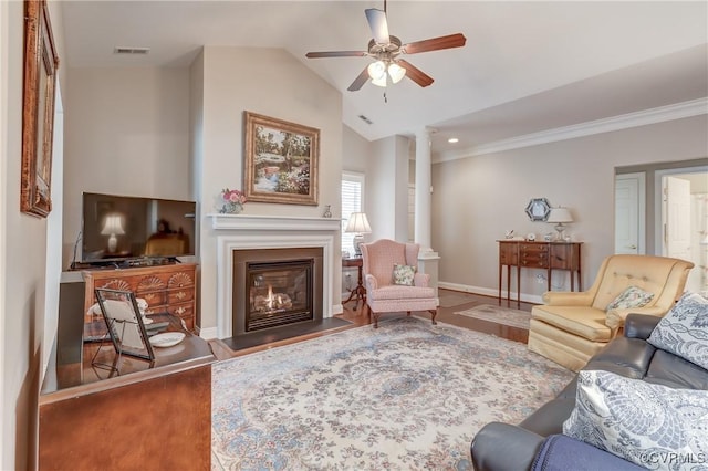 living area with baseboards, vaulted ceiling, wood finished floors, a glass covered fireplace, and a ceiling fan