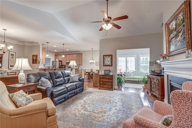 living room with wood finished floors, a fireplace, recessed lighting, vaulted ceiling, and ceiling fan with notable chandelier