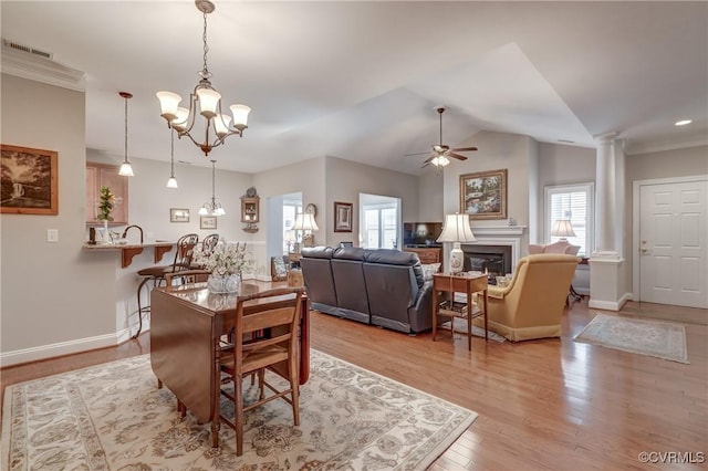 dining room featuring visible vents, a glass covered fireplace, light wood finished floors, decorative columns, and baseboards