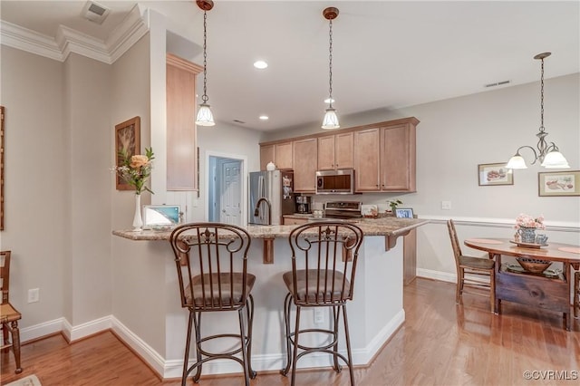 kitchen featuring a kitchen breakfast bar, light wood-style flooring, visible vents, and stainless steel appliances