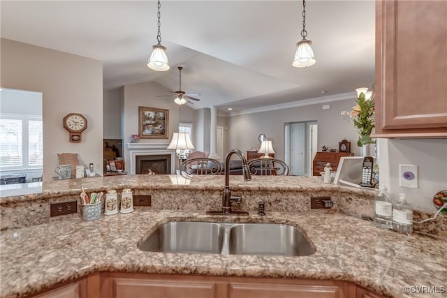 kitchen featuring a sink, a glass covered fireplace, vaulted ceiling, and hanging light fixtures