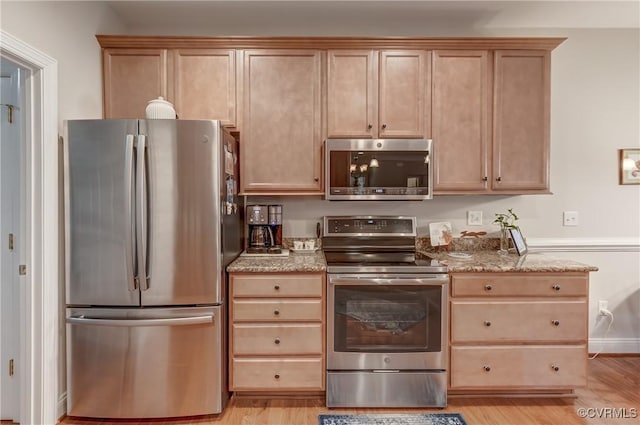 kitchen featuring light brown cabinets, light stone countertops, baseboards, light wood-style floors, and appliances with stainless steel finishes