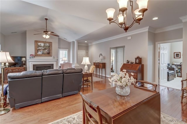 dining room with light wood-style flooring, ornamental molding, a glass covered fireplace, lofted ceiling, and ornate columns