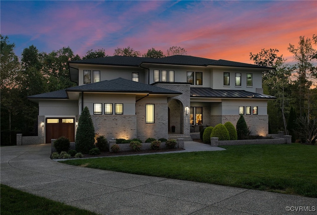 prairie-style home featuring a front yard, metal roof, driveway, an attached garage, and a standing seam roof