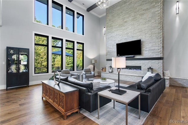 living area featuring baseboards, a high ceiling, a fireplace, wood-type flooring, and crown molding