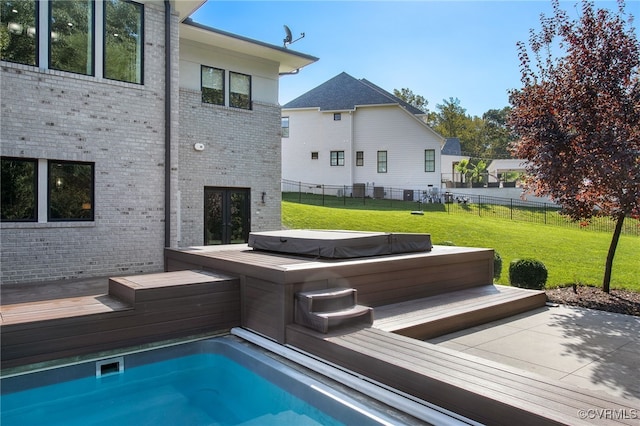 view of pool with a lawn, a wooden deck, fence, and hot tub deck surround