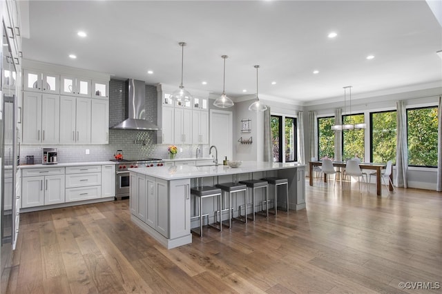 kitchen featuring white cabinetry, stainless steel range, wall chimney exhaust hood, and light countertops