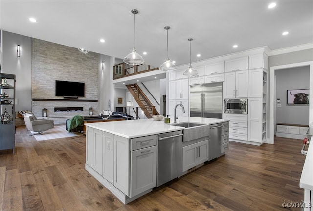 kitchen with dark wood-type flooring, white cabinets, built in appliances, and a sink