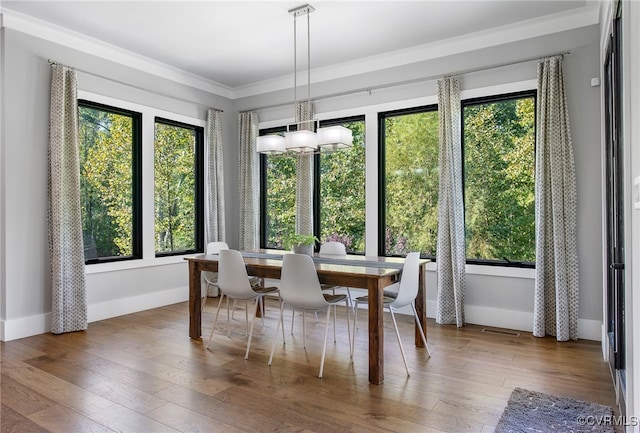 dining room with hardwood / wood-style floors, crown molding, baseboards, and a chandelier