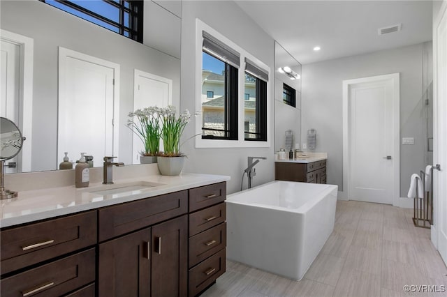 bathroom with recessed lighting, visible vents, a freestanding bath, and vanity