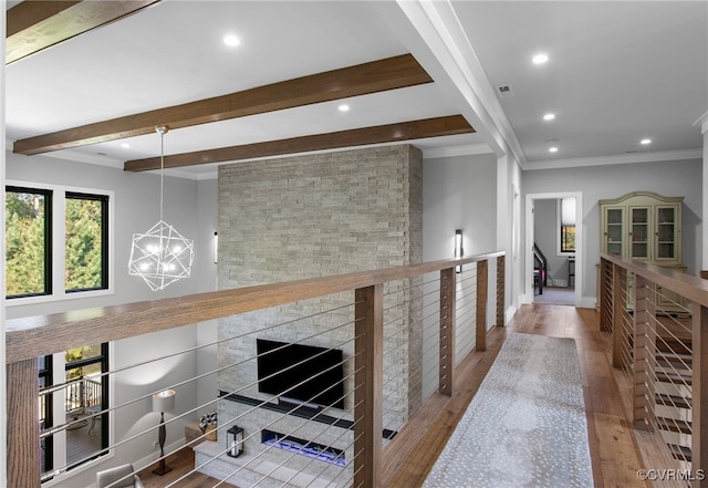 hall with beam ceiling, ornamental molding, an inviting chandelier, and wood finished floors