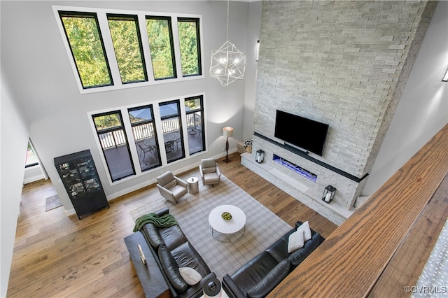 living room featuring a high ceiling, wood finished floors, baseboards, and a chandelier