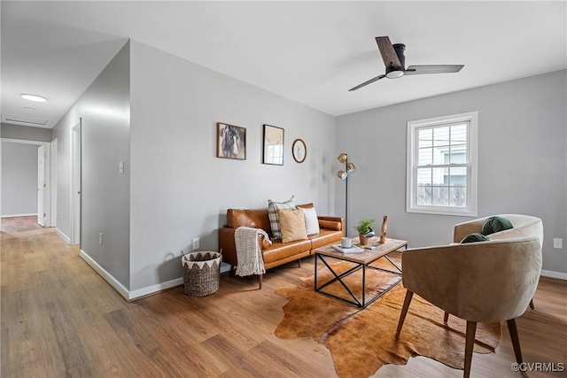 living room with a ceiling fan, baseboards, and wood finished floors