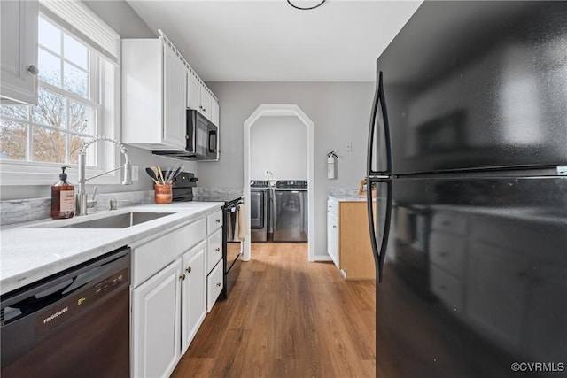 kitchen featuring black appliances, light countertops, independent washer and dryer, and a sink