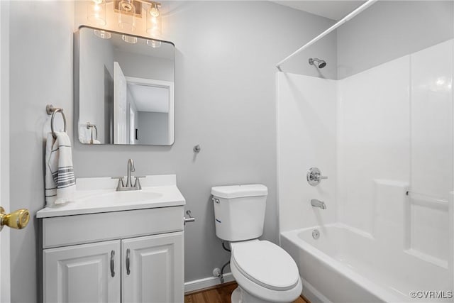 bathroom featuring toilet, wood finished floors, baseboards, bathtub / shower combination, and vanity