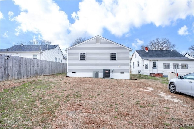 back of property with central AC unit, fence, and crawl space