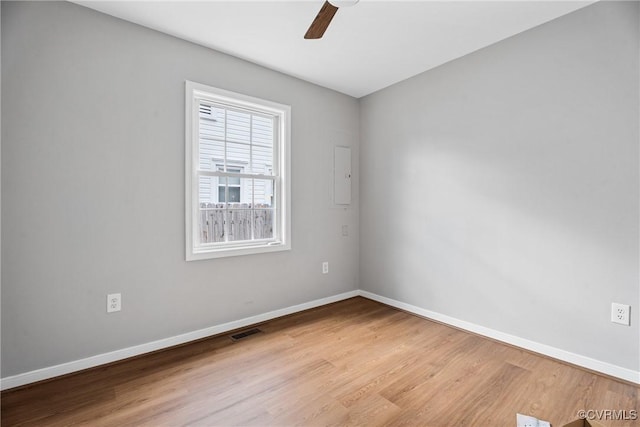 empty room featuring wood finished floors, visible vents, and baseboards