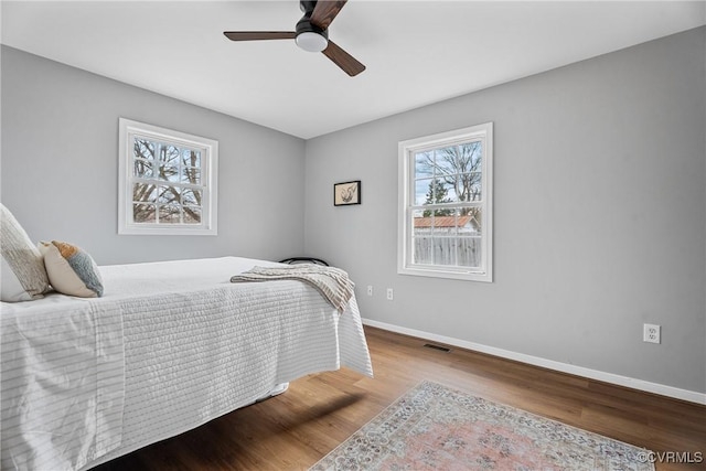 bedroom featuring visible vents, a ceiling fan, baseboards, and wood finished floors