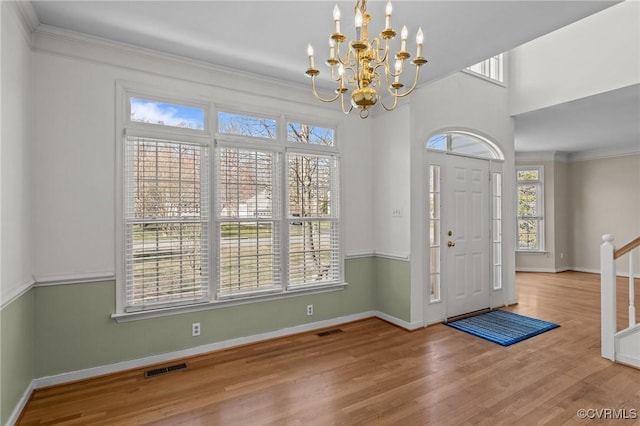 foyer entrance featuring ornamental molding, wood finished floors, visible vents, and baseboards