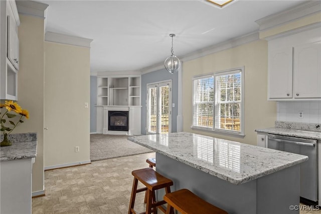 kitchen with stainless steel dishwasher, a glass covered fireplace, a kitchen breakfast bar, and ornamental molding