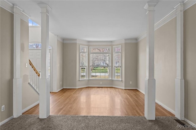 foyer with wood finished floors, crown molding, baseboards, stairs, and ornate columns