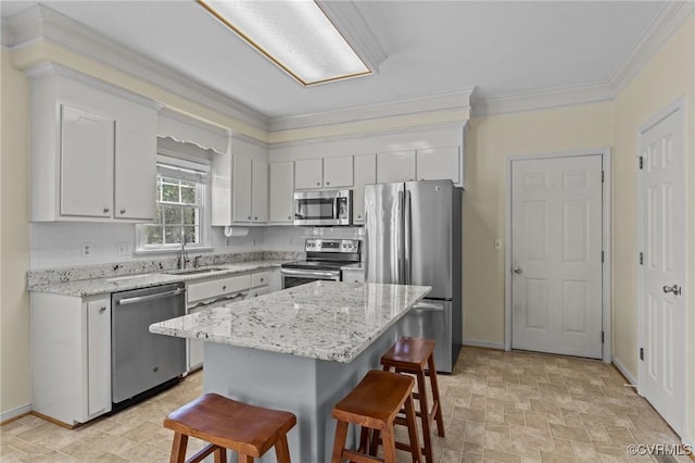 kitchen with a breakfast bar, a sink, stone finish flooring, appliances with stainless steel finishes, and crown molding