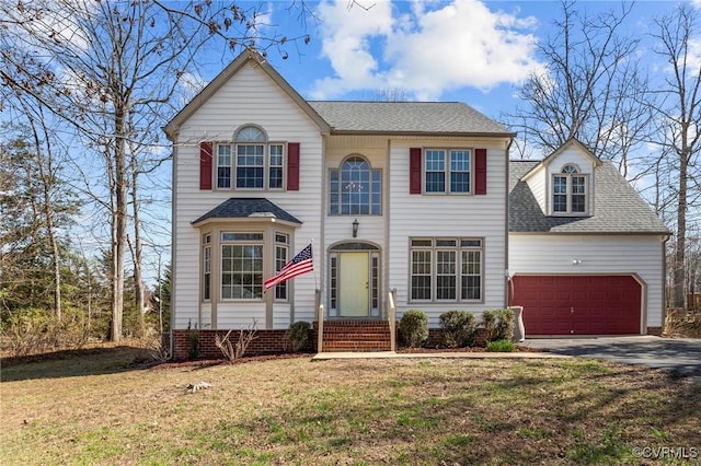 view of front of house featuring driveway, a front yard, an attached garage, and a shingled roof