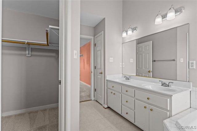 bathroom with a sink, a walk in closet, baseboards, and double vanity