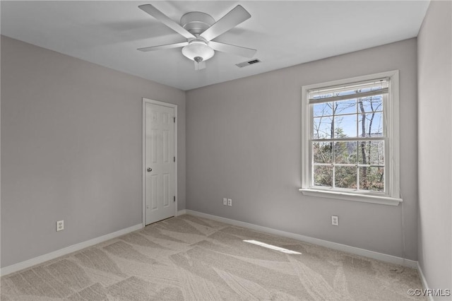 spare room with visible vents, light colored carpet, baseboards, and ceiling fan