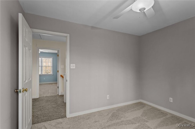 spare room featuring carpet flooring, attic access, and baseboards