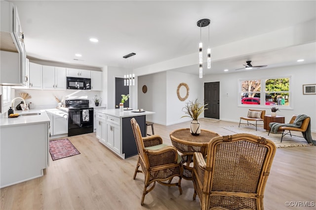 kitchen with black appliances, a sink, light wood-style floors, white cabinets, and light countertops