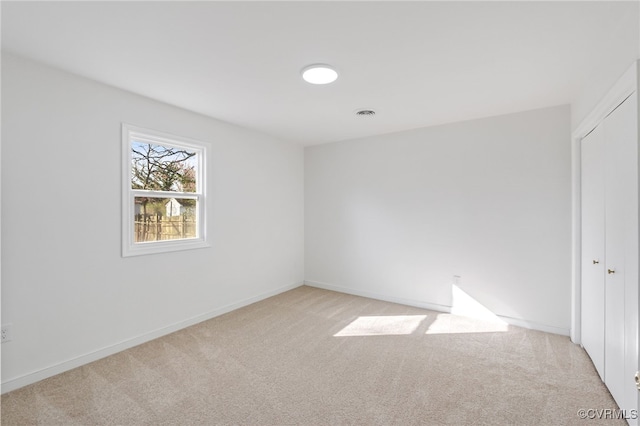 empty room with visible vents, baseboards, and light carpet