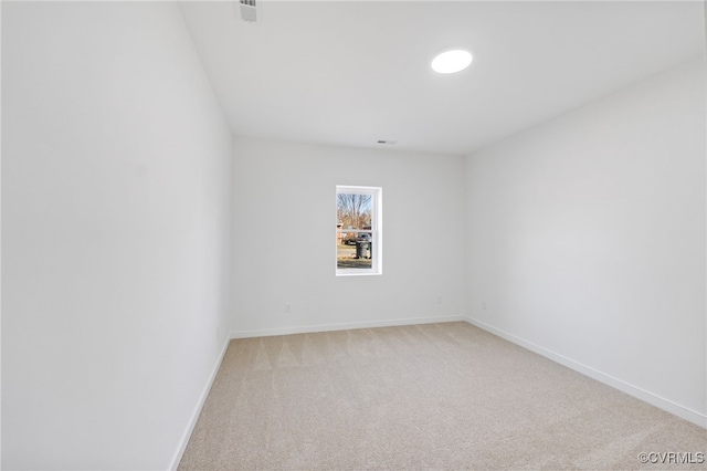 spare room with baseboards, light carpet, and visible vents