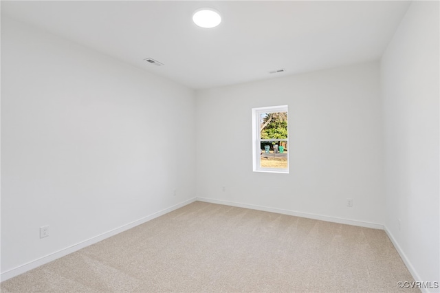 spare room featuring visible vents, baseboards, and light carpet