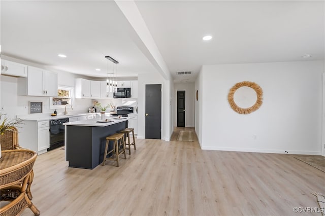 kitchen featuring black appliances, white cabinets, visible vents, and a sink