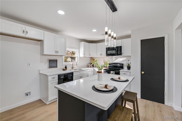 kitchen featuring black appliances, white cabinets, light wood finished floors, and a sink