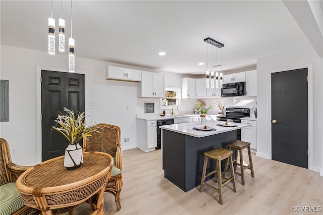 kitchen with light wood finished floors, light countertops, white cabinets, black appliances, and a sink