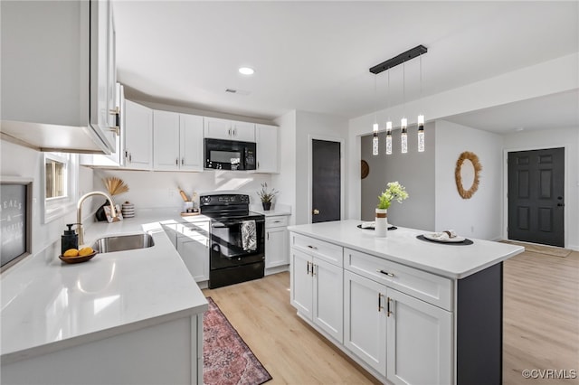 kitchen featuring black appliances, white cabinets, light wood-style flooring, and a sink