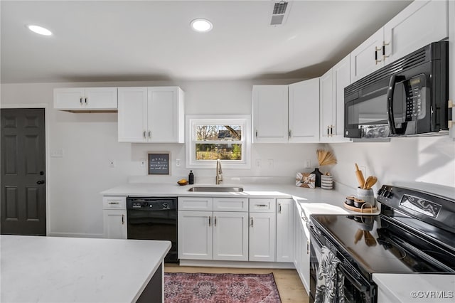 kitchen featuring recessed lighting, a sink, black appliances, white cabinets, and light countertops