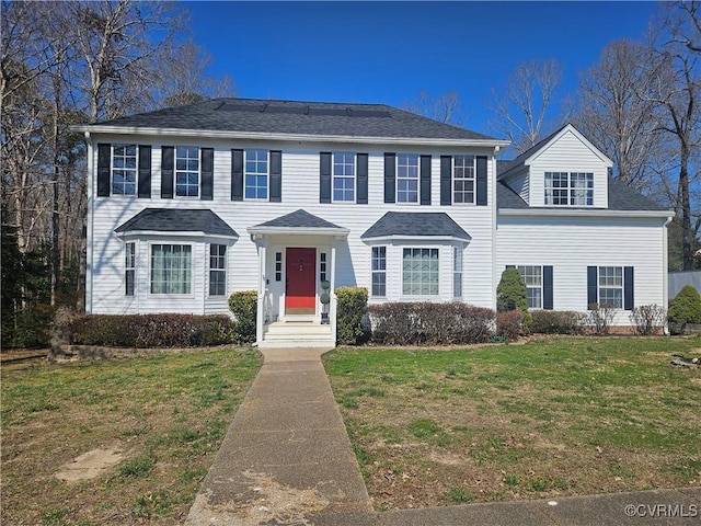 colonial-style house featuring a front yard and a shingled roof