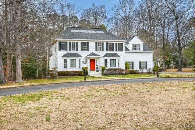 colonial home featuring driveway and a front lawn