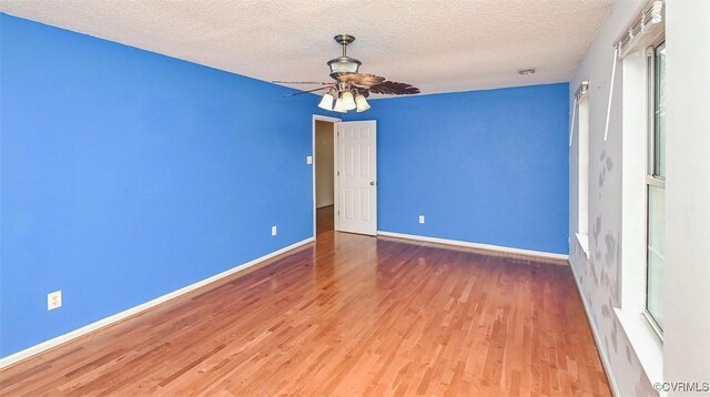 interior space featuring baseboards, a textured ceiling, ceiling fan, and wood finished floors