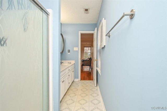 full bathroom featuring baseboards, a shower with door, tile patterned floors, and vanity